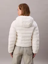 Campera puffer ligera Calvin Klein de color blanco, con diseño acolchado horizontal, capucha integrada y cierre frontal con cremallera. Presenta el logo de la marca bordado en el pecho.