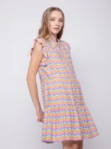 Vestido corto con estampado floral multicolor, cuello tipo camisa y cierre frontal con botones. Presenta volados en las sisas y un diseño de falda con volados en el ruedo.
