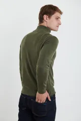Sweater verde oliva de tejido acrílico con textura similar al cashmere, corte clásico, cuello alto con cierre metálico y tirador de cuerina ecológica.