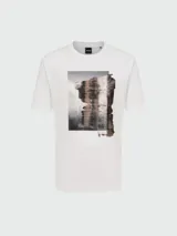 Remera de algodón blanca con cuello redondo y manga corta. Presenta un estampado gráfico central con efecto de pincelada abstracta y paisaje urbano.
