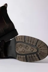 Bota tipo Chelsea de cuero color marrón oscuro con efecto desgastado, paneles laterales elásticos y suela de goma antideslizante.