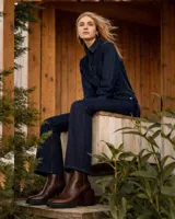 Botín de cuero vacuno color negro, con diseño combinado de cuero liso en la parte delantera y cuero con textura de reptil en el talón. Cuenta con un taco cuadrado de madera, cierre metálico en la parte posterior y suela de goma.