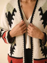 Cardigan crudo de tejido de punto con motivos navajo en rojo, negro y verde claro, sin botones y mangas largas.