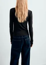 Cardigan de punto fino color gris oscuro, con cuello barco, diseño entallado, manga larga y cierre frontal de botones pequeños.