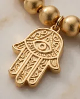 Pulsera de acero italiano con baño de oro, compuesta por una cadena de eslabones de bolitas y un dije colgante en forma de mano de Hamsa.