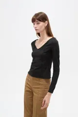 Remera negra de manga larga y calce al cuerpo, confeccionada en poliéster con diseño calado y escote en V.