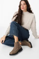 Botas cortas de cuero color visón, con suela track negra y costuras decorativas en contraste a lo largo del empeine. Cuentan con cierre lateral para facilitar su colocación.