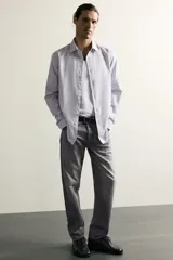 Jeans regular fit de mezclilla negra con efecto lavado, corte recto y tiro medio. Cuenta con diseño de cinco bolsillos y cierre frontal con cremallera y botón.
