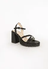 Sandalias de tacón alto y plataforma, color negro, con capellada de tiras cruzadas y cierre de hebilla en el tobillo. Cuentan con textura grabada en todo su diseño.