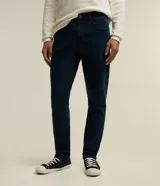Pantalón de jean corte slim, color azul oscuro, con trabillas en la cintura, cierre frontal y bolsillos laterales y traseros.
