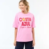 Camiseta de corte oversize color rosa, con cuello redondo y mangas cortas. Presenta un estampado frontal con la frase 'COSTA AZUL' en letras rojas y un diseño de sol, acompañado por la inscripción 'Palma de Majorque'.