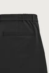 Pantalón regular fit color negro de corte recto, con cintura elástica en los laterales, trabillas, bolsillos frontales y cierre con botón y cremallera.