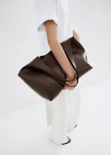 Bolso tipo tote marrón de diseño estructurado, fabricado en poliuretano con acabado texturizado, asa doble de hombro y gran capacidad de almacenamiento.