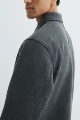 Sobrecamisa de fieltro color gris oscuro, con cuello, cierre bidireccional y bolsillos insertados en la parte delantera. Presenta un corte estándar y no tiene forro.
