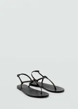 Sandalias planas negras con tiras finas y detalle de tachas doradas.
