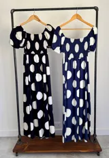 Vestido largo de lunares con escote bote y hombros descubiertos, mangas cortas abullonadas, cuerpo con nido de abeja y falda amplia.