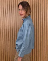 Camisa de algodón color blanco, con cuello alto con volados, mangas tres cuartos con detalles de bordado ingles y cierre frontal con botones de nácar.