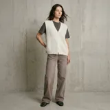 Chaleco de punto color crema con escote en V y cierre frontal con botones. Presenta un diseño sin mangas y corte holgado.