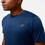 Remera deportiva azul jaspeado de New Balance, modelo Tenacity, para hombre. Confeccionada en tejido de poliéster suave y elástico con tecnología NB DRY de secado rápido.