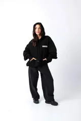 Hoodie negro de frisa con capucha y bolsillo canguro. Presenta un aplique rectangular en el pecho con texto en verde lima.