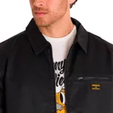 Chaqueta tipo chore de Caterpillar en color negro, confeccionada en sarga encerada. Presenta cierre frontal metálico, cuello camisero, bolsillo en el pecho con cierre y etiqueta con el logotipo de la marca. Cuenta con forro interior estampado.