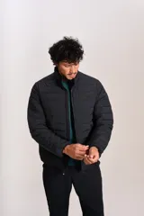 Campera acolchada negra con cierre frontal, cuello alto y diseño de costuras horizontales. Presenta un ajuste entallado y tejido exterior resistente al agua.