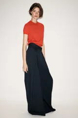 Pantalón de tiro medio con diseño wide leg, confeccionado en tejido con viscosa. Presenta un patrón de rayas diplomáticas, bolsillos laterales ocultos y detalle de pinzas pronunciadas en el delantero. Cierre frontal con cremallera, botón y ganchos metálicos.