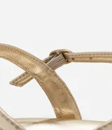 Sandalia plana dorada con tiras finas y detalle de lazos.