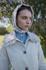 Chaqueta rosada de corte holgado con detalles en estampado de cuadros escoceses en el cuello, puños y solapas de los bolsillos. El cuello presenta un acabado con volados y el cierre es frontal con botones.