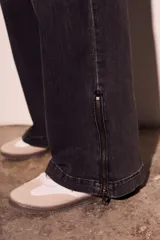 Pantalón de jean negro con efecto desgastado, corte wide leg y cierre con cremallera en los tobillos.