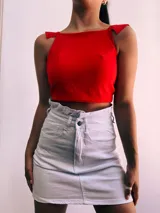 Crop top negro con textura brillante, breteles anchos con volados y espalda descubierta que se ata con lazos.