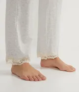 Pijama largo de dos piezas en tejido viscolycra. La blusa es de manga larga con cuello en V y detalles de encaje. El pantalón es liso con cintura elástica y encaje en el ruedo.