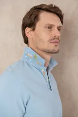 Chomba azul de piqué de algodón con cuello polo, tapeta de dos botones con diseño estampado en el interior y mangas cortas. Corte clásico.