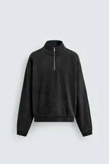 Sudadera de corte boxy fit con cuello subido y cierre frontal de cremallera. Presenta manga larga, acabado en rib en puños y ruedo, y un efecto lavado que le otorga una apariencia única.