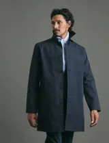 Gabardina clásica de corte recto, color beige, con cuello camisero, cierre frontal de botones y bolsillos laterales. Confeccionada en tejido técnico repelente al agua y al viento.
