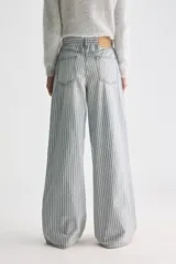 Pantalón jean de tiro medio y corte holgado con pernera ancha, diseño a rayas verticales celestes y blancas, confeccionado en algodón rígido.