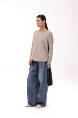 Sweater de silueta amplia y largo medio, con cuello redondo, mangas largas y detalle de botones decorativos en los laterales. Presenta un diseño de tejido de punto con caída relajada.