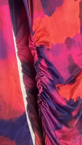 Vestido midi ajustado con estampado abstracto en tonos naranja, rosa y azul. Tiene cuello alto y mangas largas.