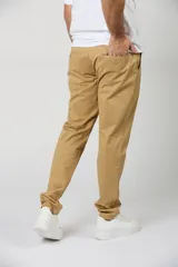 Pantalón chino de gabardina color camel, de corte recto, con bolsillos laterales y traseros, y cierre frontal con botón y cremallera.