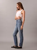 Jeans mom fit de tiro alto y pierna cónica, en denim azul con efecto deslavado. Cuenta con diseño clásico de cinco bolsillos, cierre de botón y cremallera, y detalles distintivos de la marca Calvin Klein.