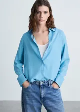 Camisa de corte recto y tejido fluido, con cuello camisero, cierre frontal de botones y mangas largas con puños abotonados.