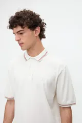 Remera polo manga corta color blanco, confeccionada en tela piqué de algodón lavado con textura extra suave. Cuenta con media cartera de botones, cuello y puños acanalados con diseño de líneas a contratono, y bordado sutil de la marca en el pecho. Calce clásico.