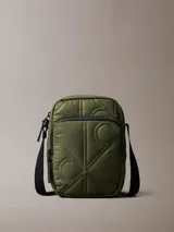 Cartera reporter color verde militar de Calvin Klein, con textura acolchada, costuras con monograma, cierre superior y bolsillo delantero con cremallera. Incluye correa ajustable negra.