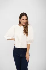 Camisa de algodón color blanco, con cuello redondo, cierre frontal oculto y mangas abullonadas de largo tres cuartos.