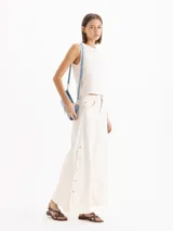 Top de denim blanco marfil, sin mangas, con escote redondo y costuras pespunteadas a la vista.