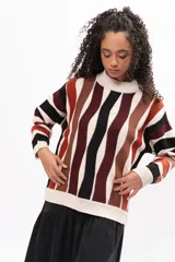 Buzo de tejido de punto con diseño de rayas verticales onduladas en tonos tierra, negro y crema. Presenta cuello redondo, mangas largas y corte holgado.