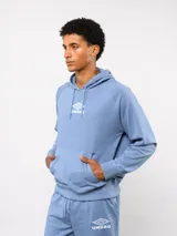 Canguro Umbro de felpa con capucha y cordones ajustables. Presenta el logo de la marca bordado en el pecho en color celeste y bolsillo frontal tipo canguro.