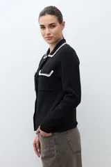 Chaqueta tejida de punto color naranja, con cuello camisero, cierre frontal de botones y dos bolsillos frontales con solapa. Presenta detalles de bordado en contraste en el cuello y los bolsillos.