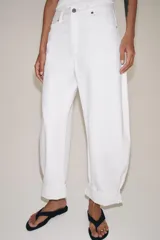 Jeans de tiro medio de corte balloon leg, color blanco, con trabillas en la cintura, diseño de cinco bolsillos, bajo con vuelta y cierre frontal con cremallera y botón.