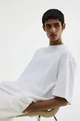 Remera blanca de algodón pesado, corte oversized, con cuello redondo ribeteado, hombros caídos y bajo recto.